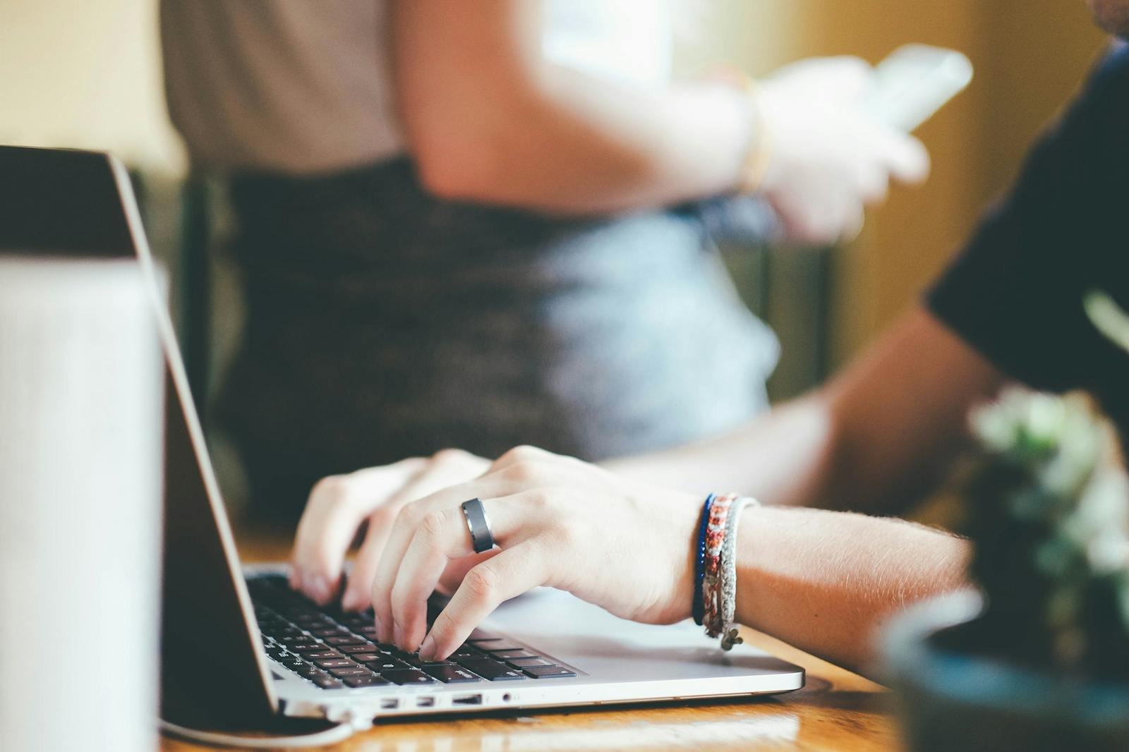 Close-up of hands typing on a laptop with a blurred background.